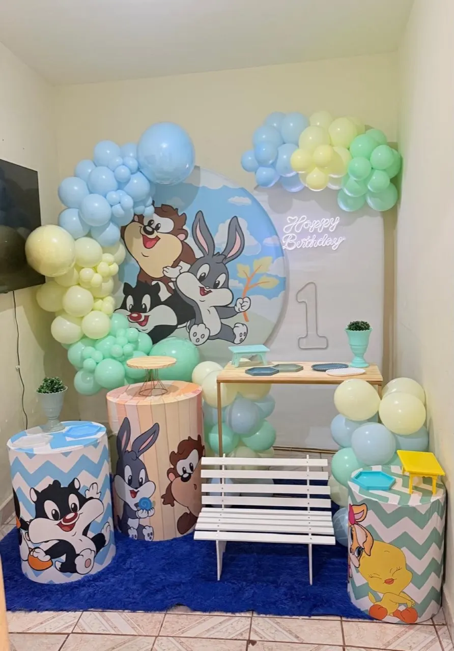Decoração Completa de 1 ano com tema Looney Tunes baby: painel redondo, arco de balões em tons pastel, cilindros e letreiro Happy Birthday