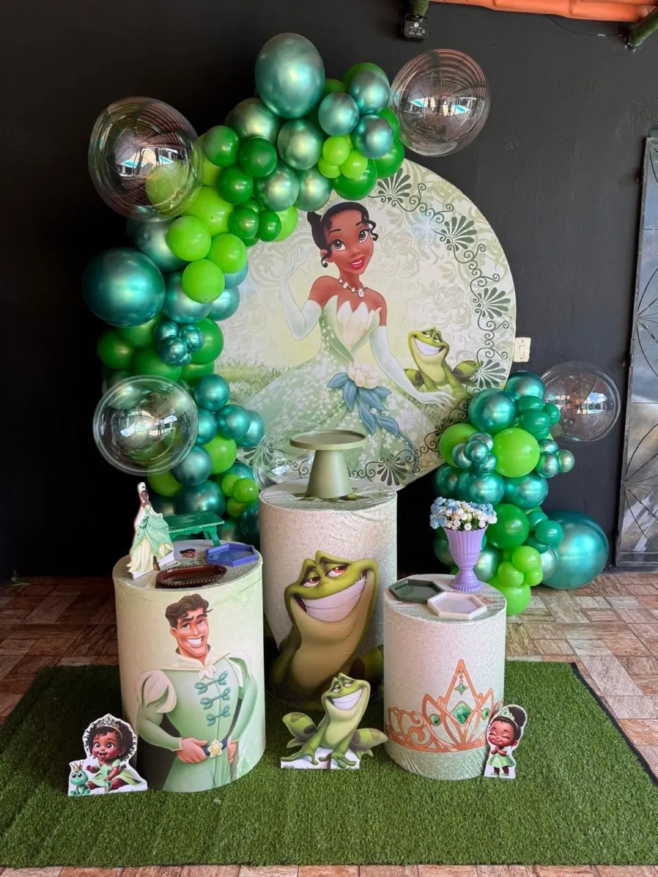 Decoração Completa com tema da Princesa Tiana: painel redondo, arco de balões verdes e cromados, três cilindros e displays do tema
