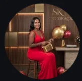 Fundadora da SK Decorações ao lado de uma decoração com balões dourados e vermelhos